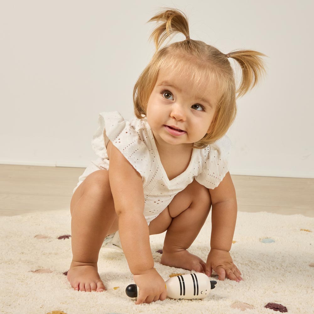 Miniland - Zebra rattle – bambina che gioca con il sonaglio sul tappeto